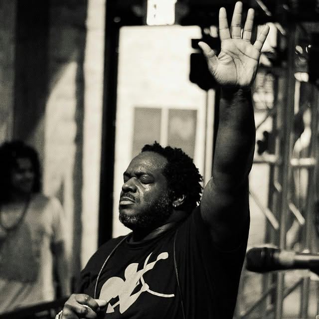 Black and white photograph of a singer with hand raised mid-song