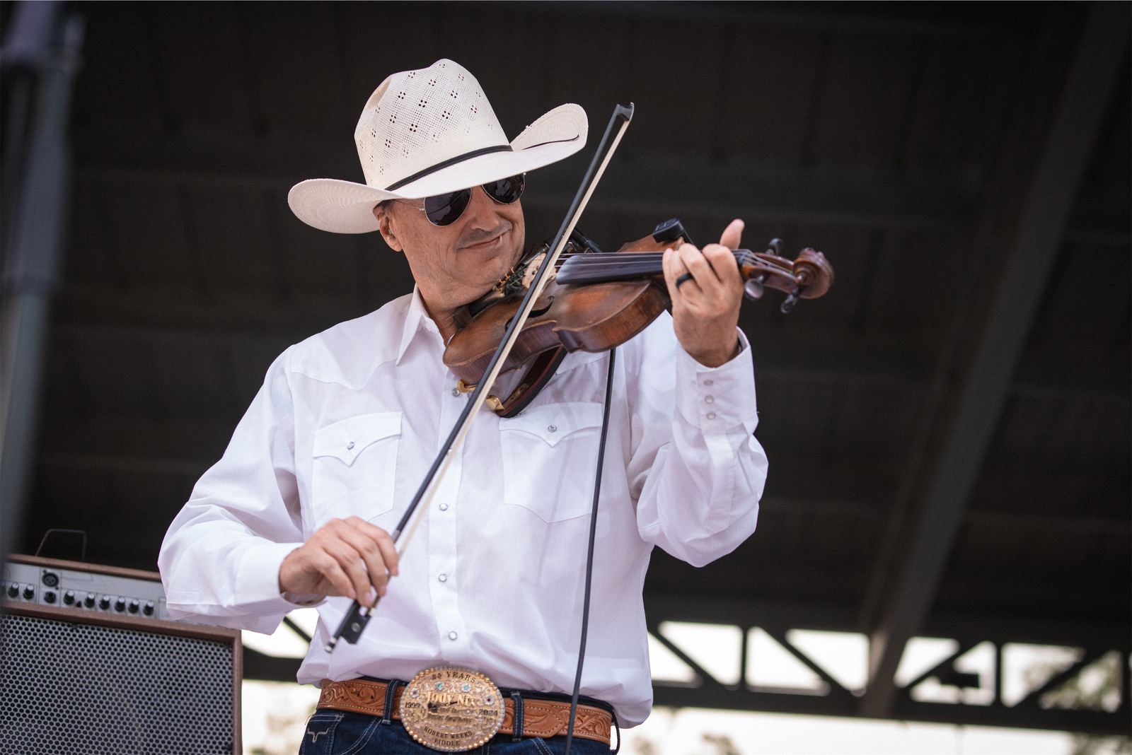 Fiddle player in a cowboy hat performing at a Texas festival at golden hour
