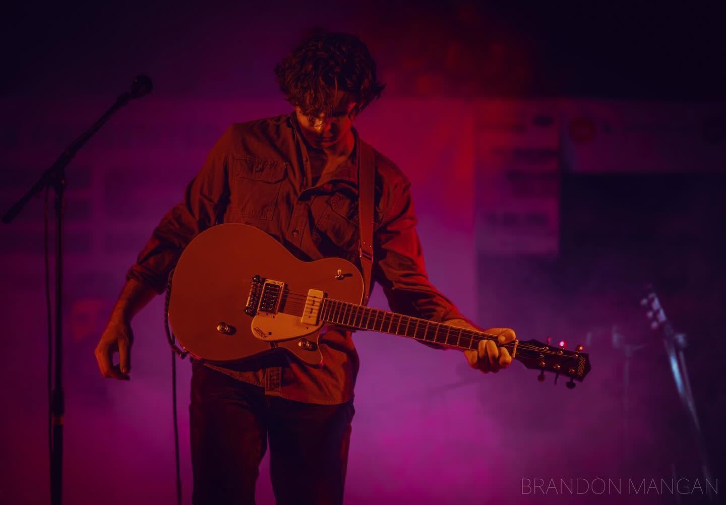 Guitarist bathed in purple and magenta stage wash