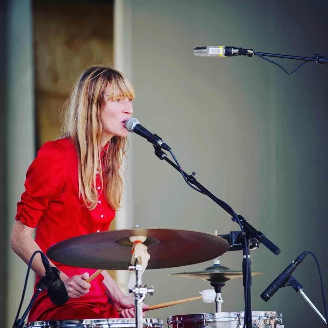 Singer in red performing at the drum kit