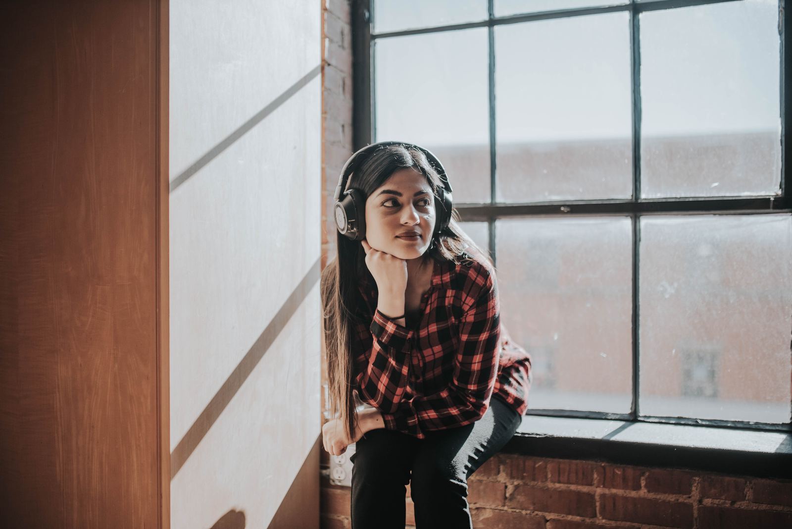 Lifestyle photography of wireless headphones worn by a window