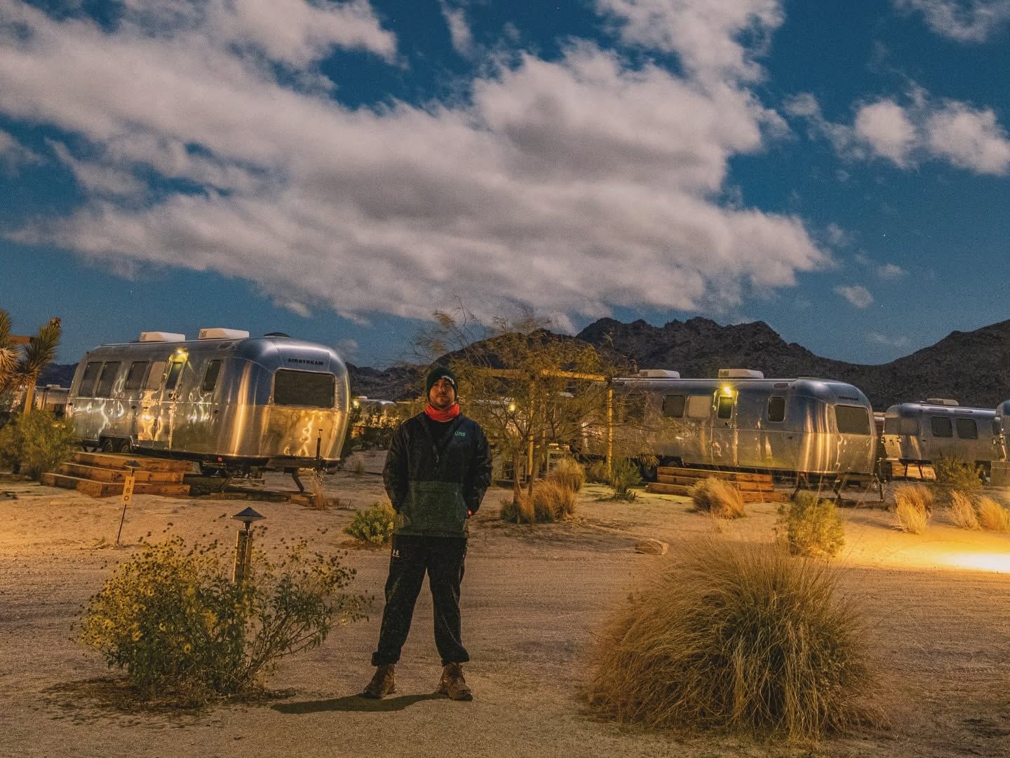 Brandon standing among Airstream trailers at night in Joshua Tree